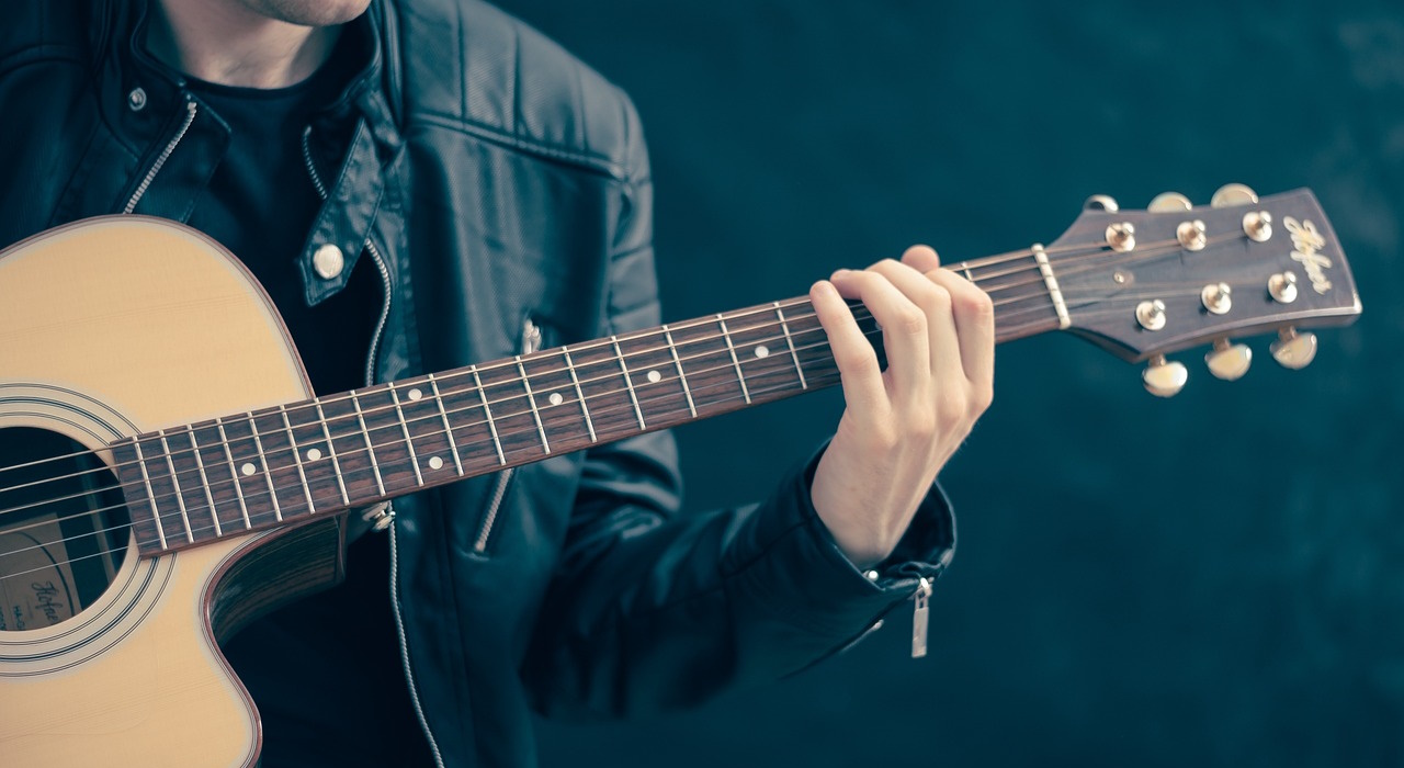 A man wearing a leather jacket, playing a guitar